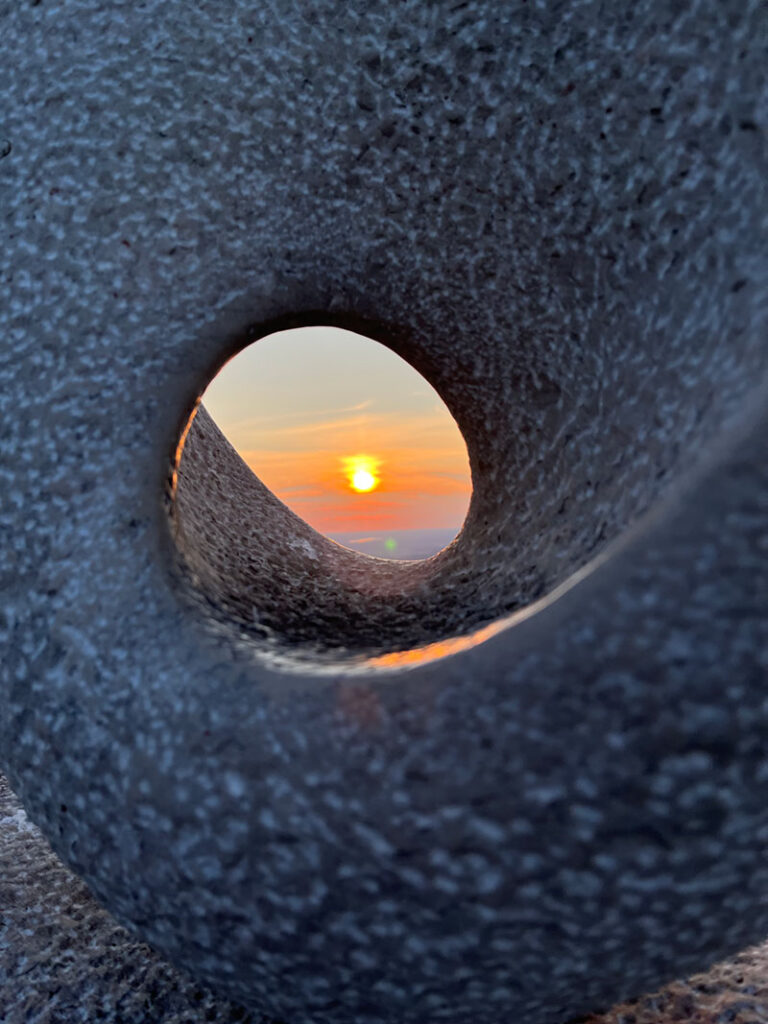 Blick auf die untergehende Sonne durch ein Loch in einem Felsen als Symbol für Unternehmensberatung Business Consulting - aus Sicht von Michael Gruböck